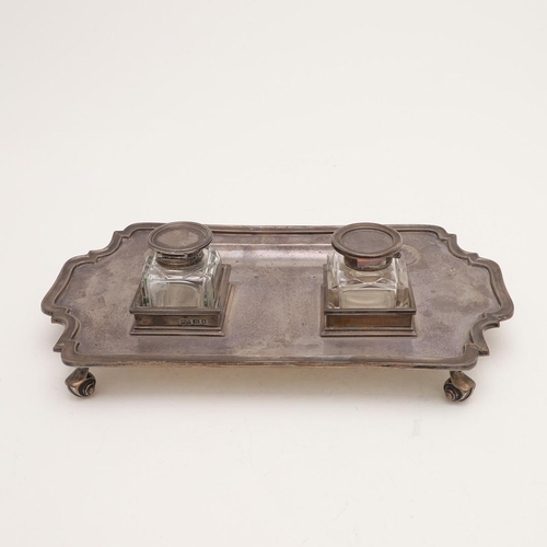 115 - A GEORGE V SILVER INKSTAND. of shaped rectangular outline, with a moulded border, fitted with two no... 