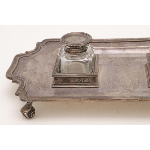 115 - A GEORGE V SILVER INKSTAND. of shaped rectangular outline, with a moulded border, fitted with two no... 