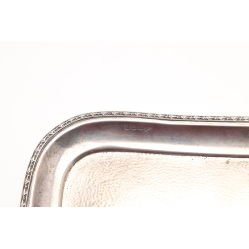 122 - AN EDWARDIAN SILVER DRESSING TABLE TRAY. shaped rectangular outline, with a spot-hammered centre and... 