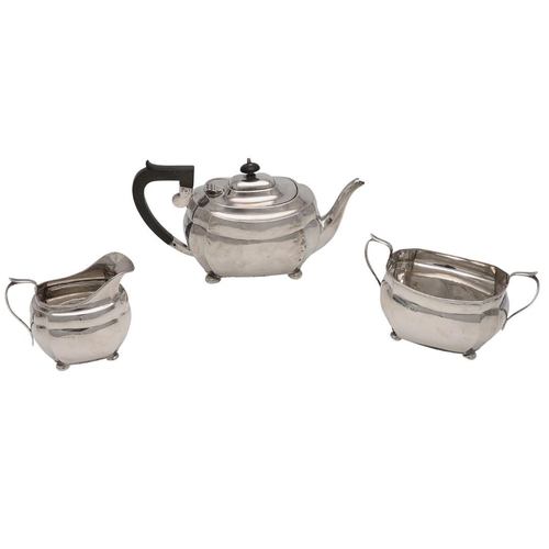 130 - A GEORGE V THREE-PIECE SILVER TEA SET. rounded rectangular, with cut corners and raised on bun feet,... 