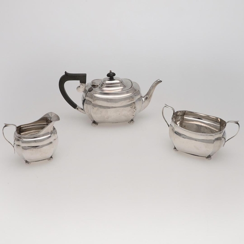 130 - A GEORGE V THREE-PIECE SILVER TEA SET. rounded rectangular, with cut corners and raised on bun feet,... 