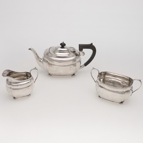 130 - A GEORGE V THREE-PIECE SILVER TEA SET. rounded rectangular, with cut corners and raised on bun feet,... 