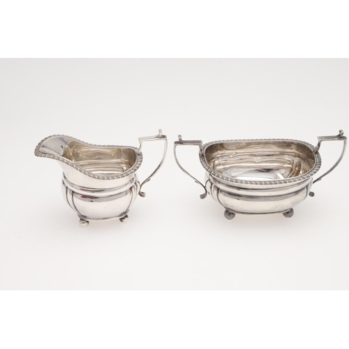 131 - AN EDWARDIAN SMALL OR BACHELOR'S THREE PIECE SILVER TEA SET. rounded rectangular, with gadrooned bor... 