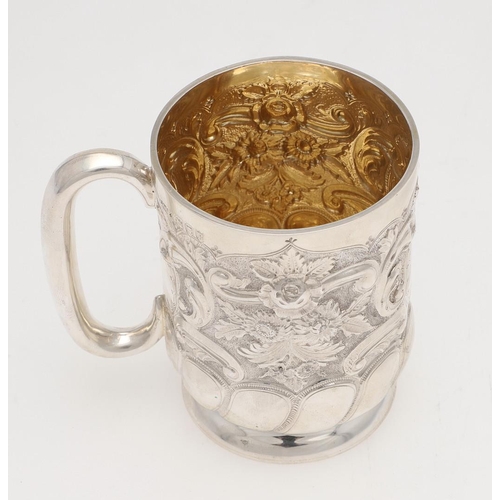 141 - A VICTORIAN SILVER MUG. circular form, embossed & chased with foliate scroll decoration and a vacant... 