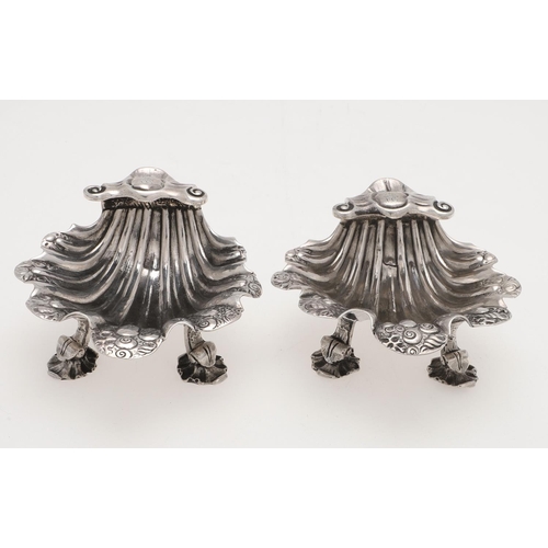 153 - A PAIR OF GEORGE II/ III IRISH SILVER SHELL SALTS. with chased decoration, raised on three scroll & ... 