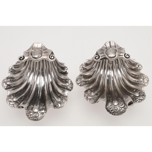 153 - A PAIR OF GEORGE II/ III IRISH SILVER SHELL SALTS. with chased decoration, raised on three scroll & ... 