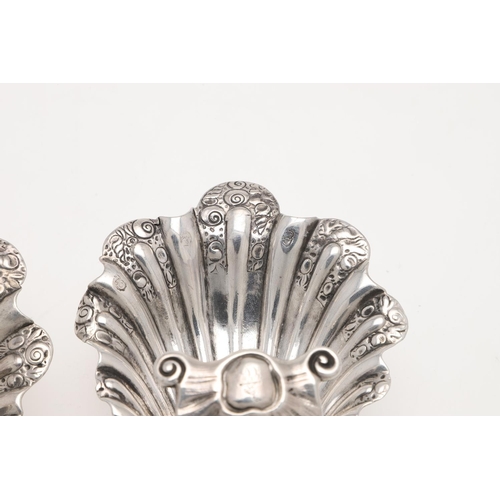 153 - A PAIR OF GEORGE II/ III IRISH SILVER SHELL SALTS. with chased decoration, raised on three scroll & ... 