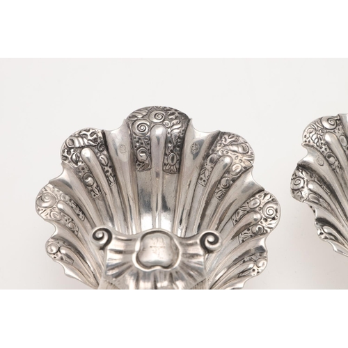 153 - A PAIR OF GEORGE II/ III IRISH SILVER SHELL SALTS. with chased decoration, raised on three scroll & ... 