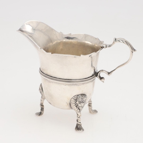 154 - A GEORGE II HELMET-SHAPED IRISH SILVER CREAM JUG. raised on three lion mask legs, with a reeded cent... 