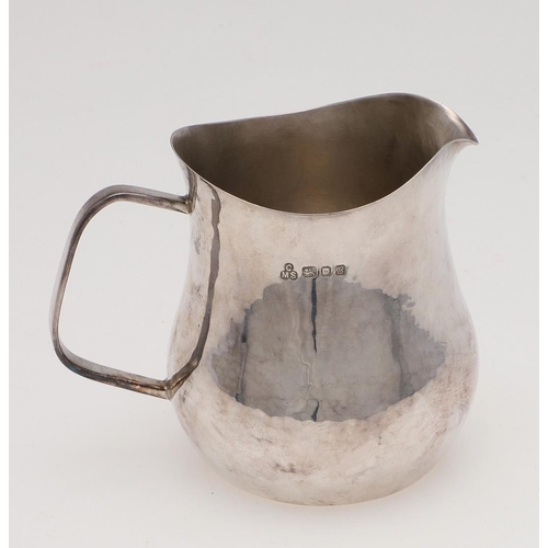 169 - A MODERN WEST COUNTRY SILVER MILK JUG. shaped circular form, with a stylised handle and a spot-hamme... 