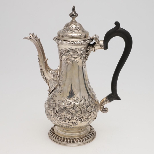 185 - A GEORGE III SILVER COFFEE POT. baluster form, with embossed & chased decoration, a scroll handle an... 