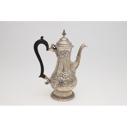 185 - A GEORGE III SILVER COFFEE POT. baluster form, with embossed & chased decoration, a scroll handle an... 