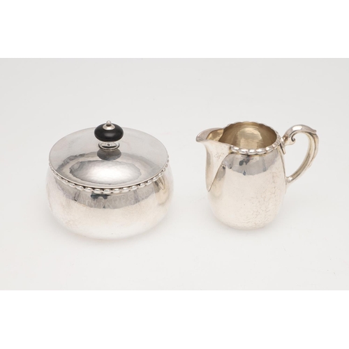 193 - AN EARLY 20TH CENTURY THREE-PIECE CONTINENTAL SILVER SUGAR & CREAM SET. with a spot-hammered finish,... 