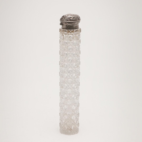 243 - A SILVER MOUNTED CUT-GLASS BOTTLE. with a long body and the hinged cover with embossed decoration & ... 