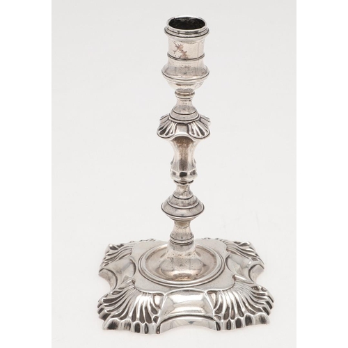 274 - A GEORGE II CAST SILVER TAPERSTICK. on a shaped square base, with shell decoration, a knopped stem a... 