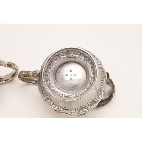 79 - A WILLIAM IV IRISH SILVER THREE-PIECE TEA SET. of circular form, with leaf-capped scroll handles, em... 