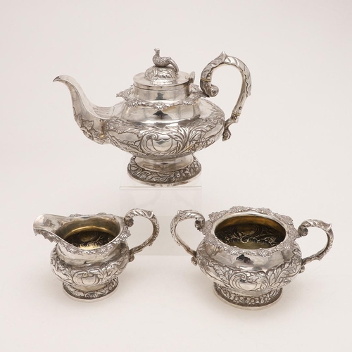 79 - A WILLIAM IV IRISH SILVER THREE-PIECE TEA SET. of circular form, with leaf-capped scroll handles, em... 