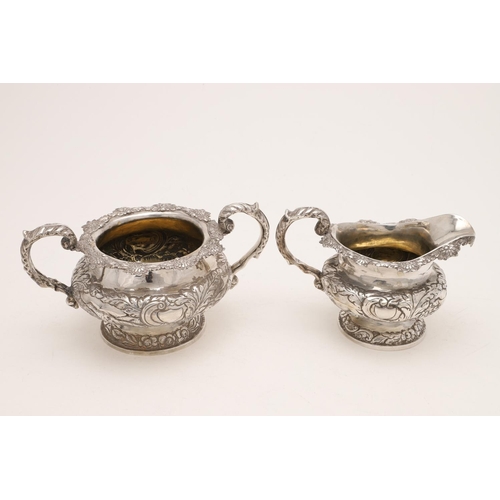 79 - A WILLIAM IV IRISH SILVER THREE-PIECE TEA SET. of circular form, with leaf-capped scroll handles, em... 