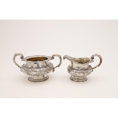 79 - A WILLIAM IV IRISH SILVER THREE-PIECE TEA SET. of circular form, with leaf-capped scroll handles, em... 