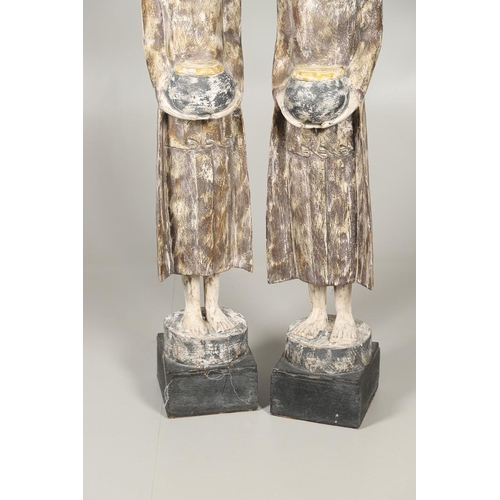 1203 - A PAIR OF THAI POLYCHROME CARVED STANDING WOODEN FIGURES OF MONKS. 20th century, each holding an off... 