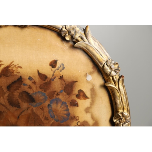 1220 - A 19TH CENTURY GILTWOOD POLE SCREEN. the oval floral silkwork panel within a carved naturalistic fra... 