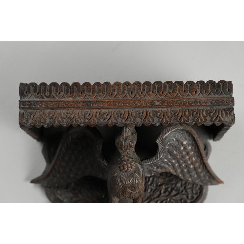 1273 - AN INDIAN CARVED HARDWOOD WALL SHELF. the ornately carved rectangular shelf on a peacock support wit... 