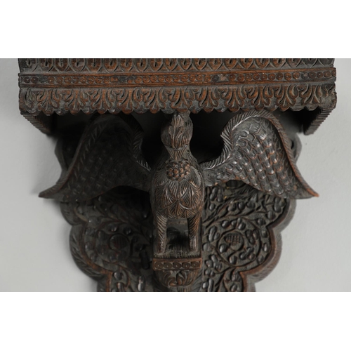 1273 - AN INDIAN CARVED HARDWOOD WALL SHELF. the ornately carved rectangular shelf on a peacock support wit... 