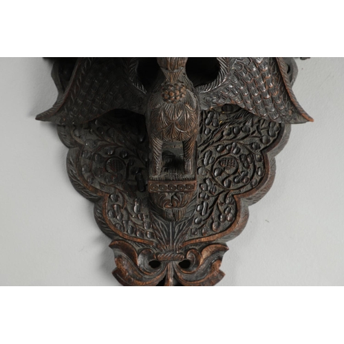 1273 - AN INDIAN CARVED HARDWOOD WALL SHELF. the ornately carved rectangular shelf on a peacock support wit... 