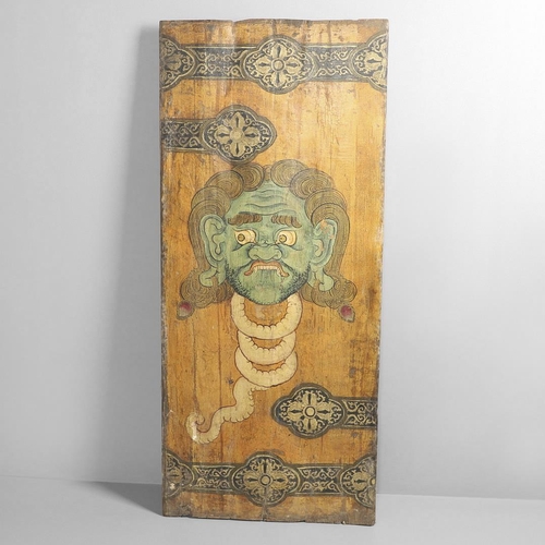 1274 - AN INDONESIAN PAINTED WOOD PANEL. decorated with the head of a blood thirsty demon and ornate 'strap... 