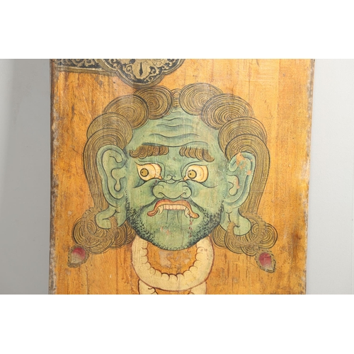 1274 - AN INDONESIAN PAINTED WOOD PANEL. decorated with the head of a blood thirsty demon and ornate 'strap... 