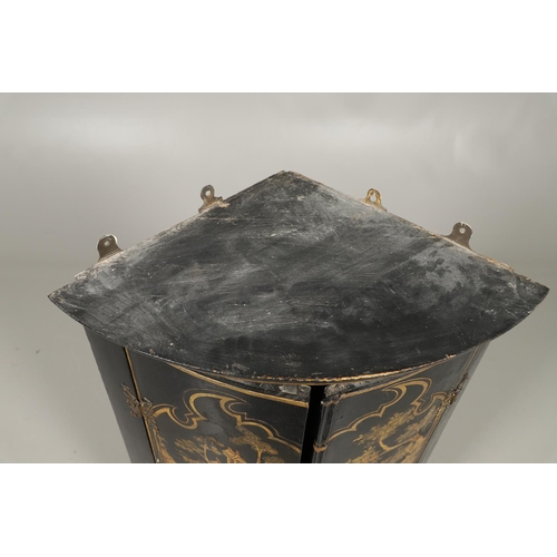 1276 - AN EARLY 20TH CENTURY BLACK CHINOISERIE HANGING CORNER CUPBOARD. the bow front doors gilt decorated ... 