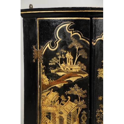 1276 - AN EARLY 20TH CENTURY BLACK CHINOISERIE HANGING CORNER CUPBOARD. the bow front doors gilt decorated ... 