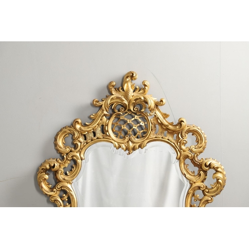 1291 - A 20TH CENTURY GILTWOOD WALL MIRROR. the heavily carved C scroll and foliate frame with a lattice an... 