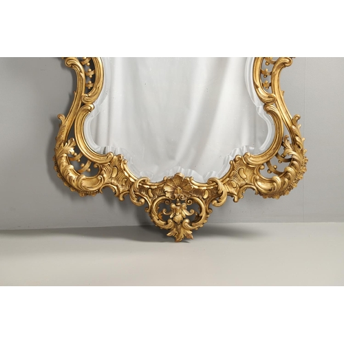 1291 - A 20TH CENTURY GILTWOOD WALL MIRROR. the heavily carved C scroll and foliate frame with a lattice an... 