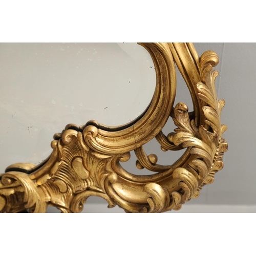 1291 - A 20TH CENTURY GILTWOOD WALL MIRROR. the heavily carved C scroll and foliate frame with a lattice an... 