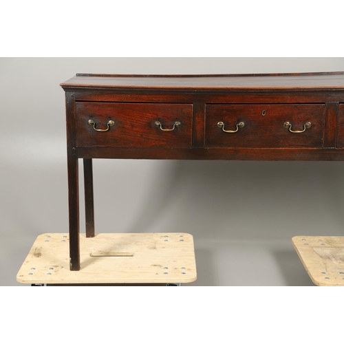 1300 - A GEORGE II OAK DRESSER BASE. the plank top over three drawers with brass handles and square legs, h... 