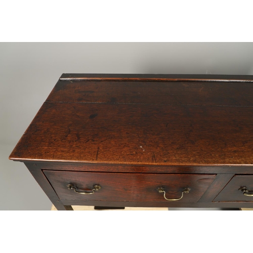 1300 - A GEORGE II OAK DRESSER BASE. the plank top over three drawers with brass handles and square legs, h... 