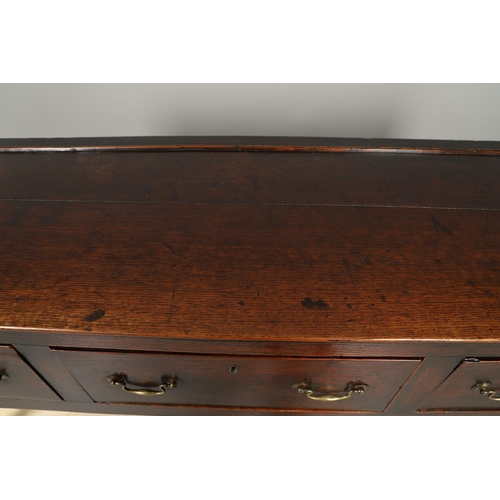 1300 - A GEORGE II OAK DRESSER BASE. the plank top over three drawers with brass handles and square legs, h... 