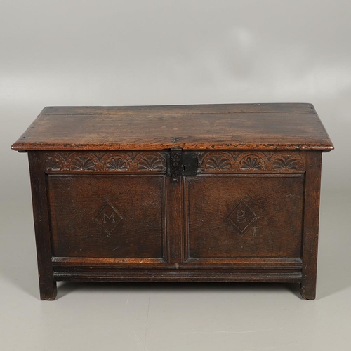 1306 - AN 18TH CENTURY OAK COFFER. the plain two plank top over a carved lunette frieze, the two panel fron... 