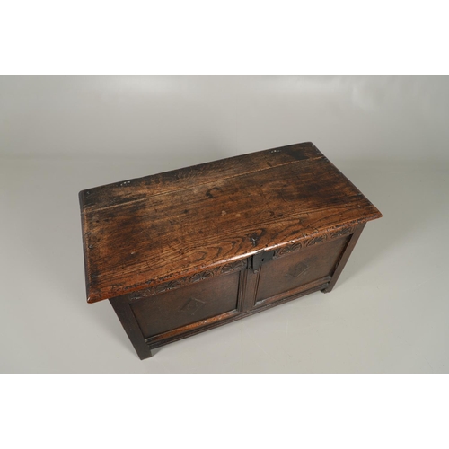 1306 - AN 18TH CENTURY OAK COFFER. the plain two plank top over a carved lunette frieze, the two panel fron... 