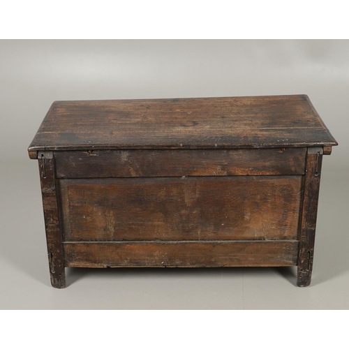 1306 - AN 18TH CENTURY OAK COFFER. the plain two plank top over a carved lunette frieze, the two panel fron... 