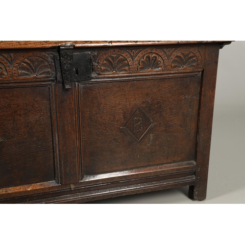 1306 - AN 18TH CENTURY OAK COFFER. the plain two plank top over a carved lunette frieze, the two panel fron... 