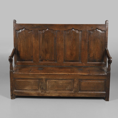 1307 - AN 18TH CENTURY OAK BOX SETTLE. the quadruple panelled back with carved arch ogee detail over a hing... 