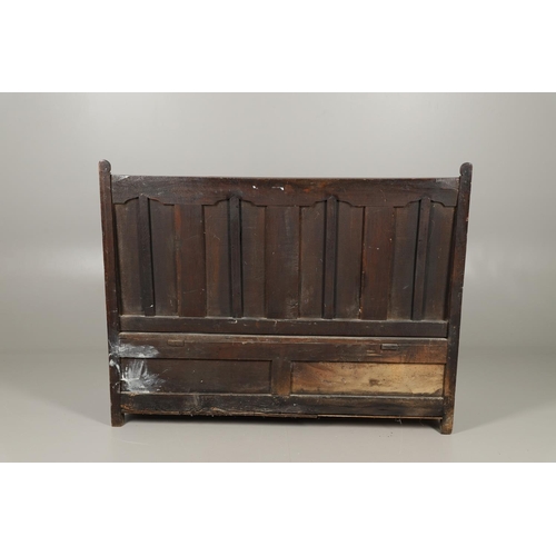 1307 - AN 18TH CENTURY OAK BOX SETTLE. the quadruple panelled back with carved arch ogee detail over a hing... 