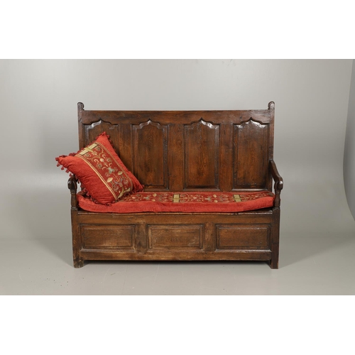 1307 - AN 18TH CENTURY OAK BOX SETTLE. the quadruple panelled back with carved arch ogee detail over a hing... 