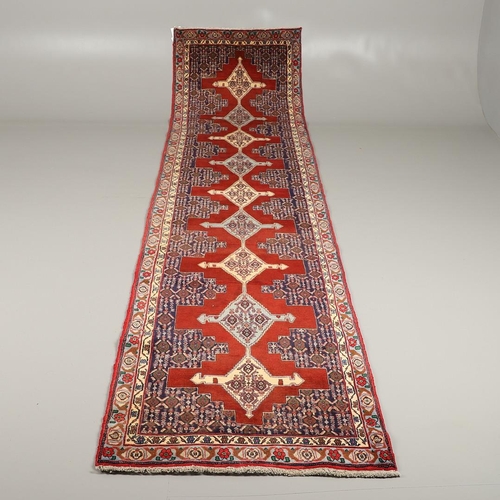 1318 - A SENNEH RUNNER, PERSIAN KURDISTAN, CIRCA 1980. the field with a column of winged diamond medallions... 