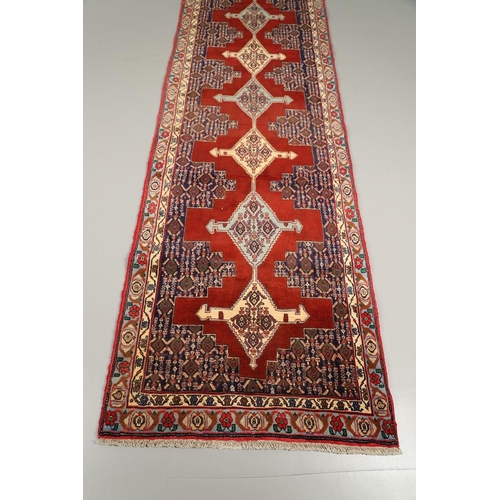 1318 - A SENNEH RUNNER, PERSIAN KURDISTAN, CIRCA 1980. the field with a column of winged diamond medallions... 