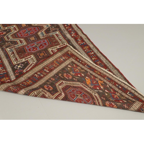 1327 - AN EAST CAUCASIAN RUG, CIRCA 1900. the charcoal field with central panel containing a column of hook... 