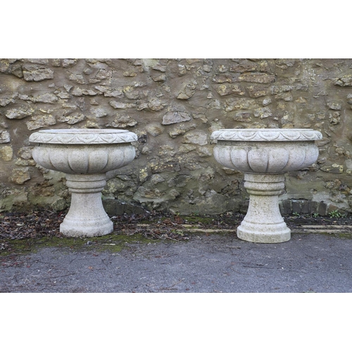 1337 - A PAIR OF LARGE CARVED GRANITE URNS. of circular lobed form, on turned column bases, height 52cm, wi... 