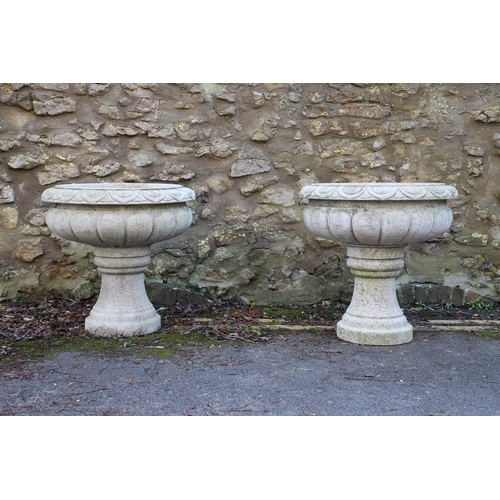 1337 - A PAIR OF LARGE CARVED GRANITE URNS. of circular lobed form, on turned column bases, height 52cm, wi... 